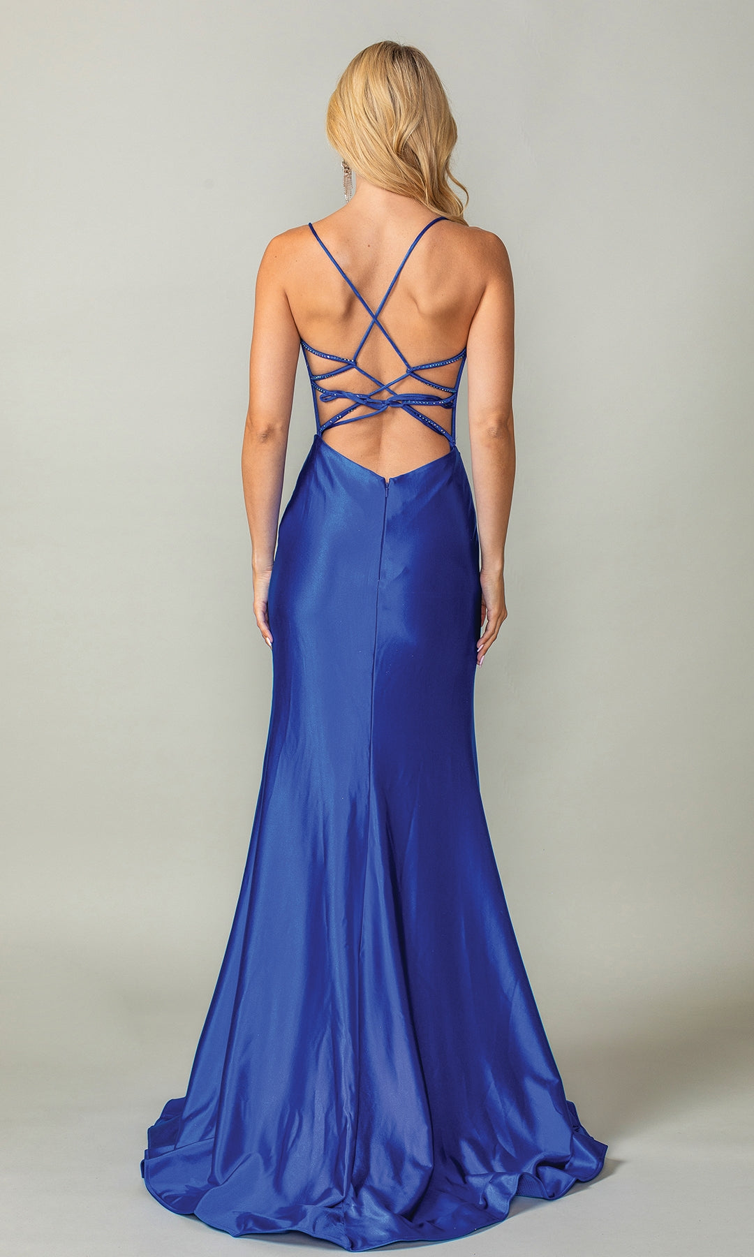 A woman faces away from the camera in the Long Prom Dress 4410 by Dancing Queen—a floor-length, royal blue satin gown with a fitted silhouette and strappy open back—set against a plain light background.